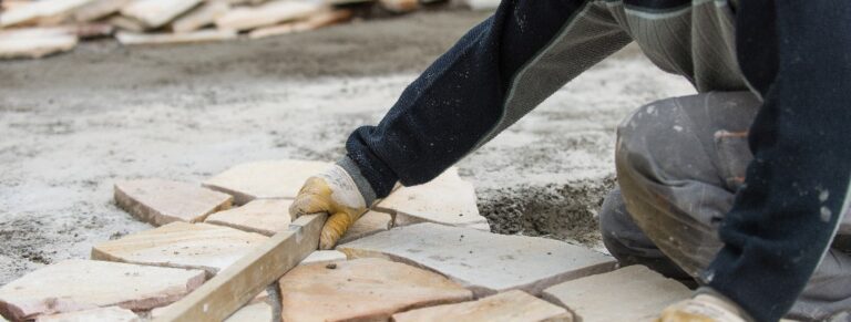 Ein Mann verbaut Terrassenplatten im Garten