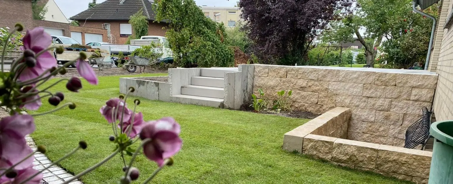 Ein gepflegter Garten mit grüner Wiese und lila Blüten im Vordergrund
